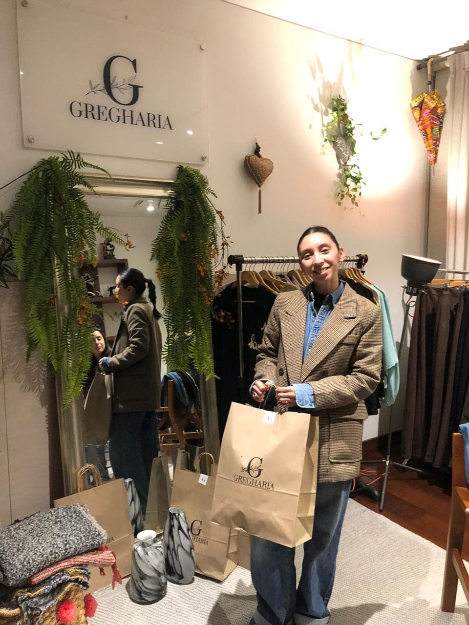 Clienta Gregharia con blazer a cuadros sosteniendo bolsas de la tienda